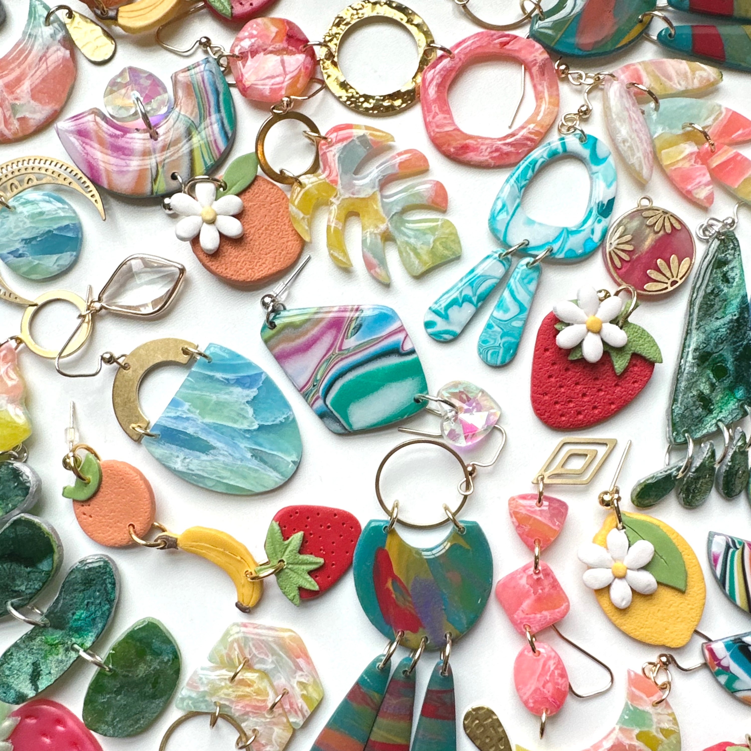 Various colorful earrings are displayed on a flat white background.